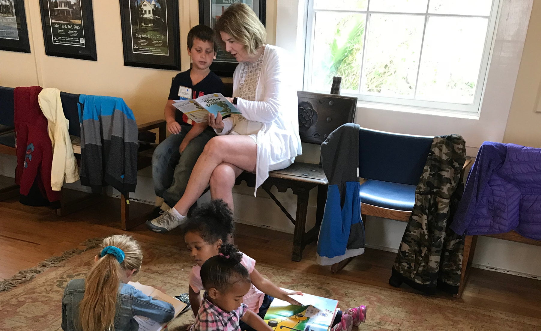 Woman reading to boy and group of girls reading